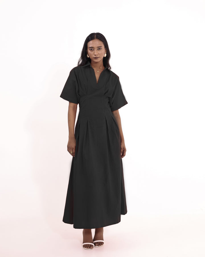 Model wearing elegant black cotton maxi dress with V-collar and pleated skirt – perfect for summer or evening wear