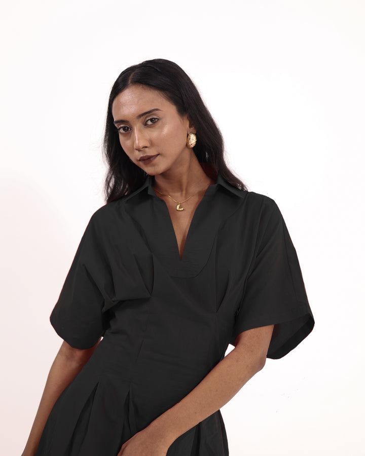 Model wearing elegant black cotton maxi dress with V-collar and pleated skirt – perfect for summer or evening wear