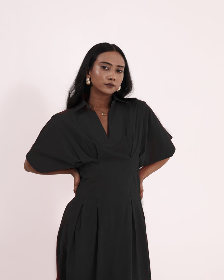 Model wearing elegant black cotton maxi dress with V-collar and pleated skirt – perfect for summer or evening wear